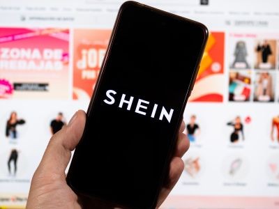 main tenan tun smartphone devant un écran d'ordinateur