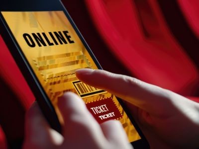 main tenant un smartphone devant des sièges d'une salle de spectacle
