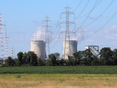 cheminées d'une centrale nucléaires, pylônes électriques  avec un champs en premier plan