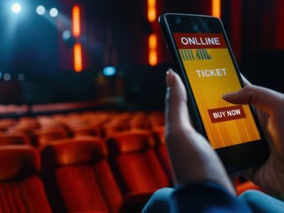 main tenant un smartphone devant des sièges d'une salle de spectacle