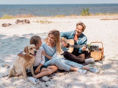 chien homme jouant d ela guitare, femme, enfant panier pique-nique sur une plade