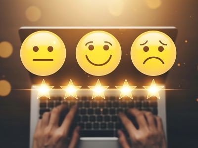 main qui pianote un clavier d'ordinateur avec au dessus 5 étoiles et un smiley qui a une expression neutre, un autre qu sourit et un 3ème qui est triste