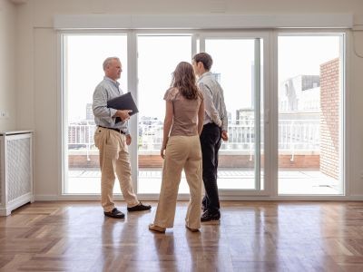 deux homme et une femme dans une pièce vide avec un balcon