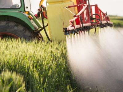 tracteur qui pulvérise des pesticides dans un champs
