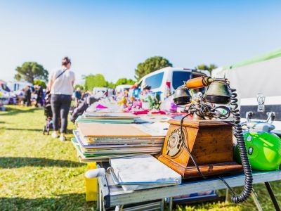 femme de dos qui pousse une poussette tables avec différents objets posés dessus
