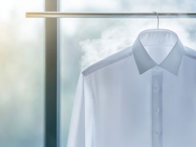 chemise sur un ceintre suspendu à une barre devant une fenêtre et de la vapeur