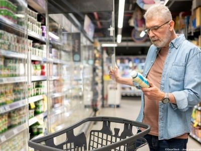 homme qui regarde une bouteille devant un rayon frais dans un supermarché