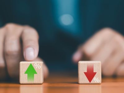 doigt qui montre un dé en bois avec une flèche vert le haut et le signe pourcentage et posé à côté dé en bois avec une flèche vers le bas et un pourcentage