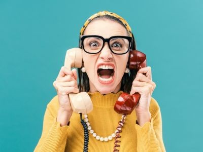 femme à lunettes qui cri  avec deux combinés de téléphone à fil