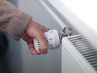 main qui tourne le thermostat d'un radiateur au gaz